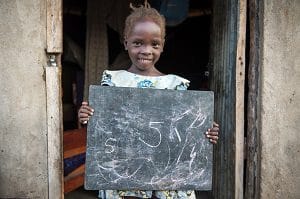 On 8 June 2016, Susan Andua, 5, plays in the village, outside of her home in Nimule, South Sudan.  I asked her that too! Susans mother Florence said with a laugh as she continued to press the laundry with a small charcoal-heated iron. The bubbly Susan had just said she wanted to be a pilot when she grew up. Her mother explained: One day she asked her teacher what makes those planes in the sky go, and her teacher said it was humans, people who go to school a lot. My daughter decided she wanted to be a pilot, and she would go to school a lot. However, Susan was not at school this week as she has an eye problem that stops her going to school at the moment. It hurts, but my mother took me to see the clinic. She writes confidently for her age on her own chalkboard, a small piece of chalk borrowed from a neighbor. After writing her age, she continued writing to 10. When I dont go to school I help my mother with the maize, and in the house. But mostly I like my chalkboard and doing my homework. Oh, and football.