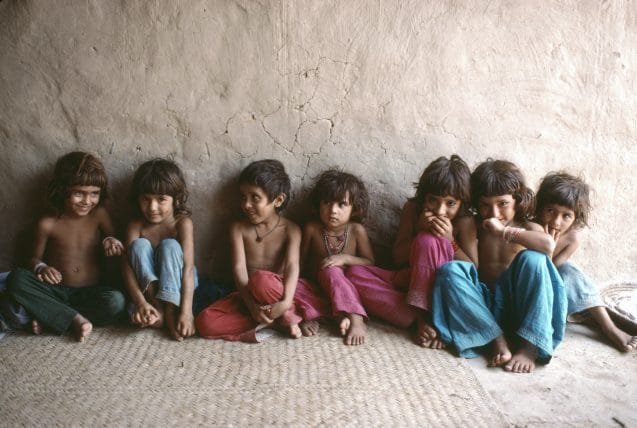 In 1988 in Pakistan, children sit by a wall in a camp for Afghan refugees in the north-western city of Peshawar.