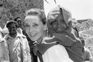 UNICEF Goodwill Ambassador Audrey Hepburn smiles as she carries a child on her back, in the northern town of Mehal Meda in Shoa Province. Ms. Hepburn was visiting a food distribution centre in the town. In 1988, internationally known film actor and UNICEF Goodwill Ambassador Audrey Hepburn travelled to Ethiopia on her first official UNICEF mission, to raise awareness of the impact of the continuing drought on the country's children and women. During her trip, sponsored by the United States Committee for UNICEF, Ms. Hepburn visited UNICEF-assisted health clinics and supplementary feeding programmes, 'food-for-work' projects, an income-generating project and an orphanage for children who have been abandoned or orphaned in this region during the drought. Ms. Hepburn was appointed a UNICEF Goodwill Ambassador on 9 March of this year.